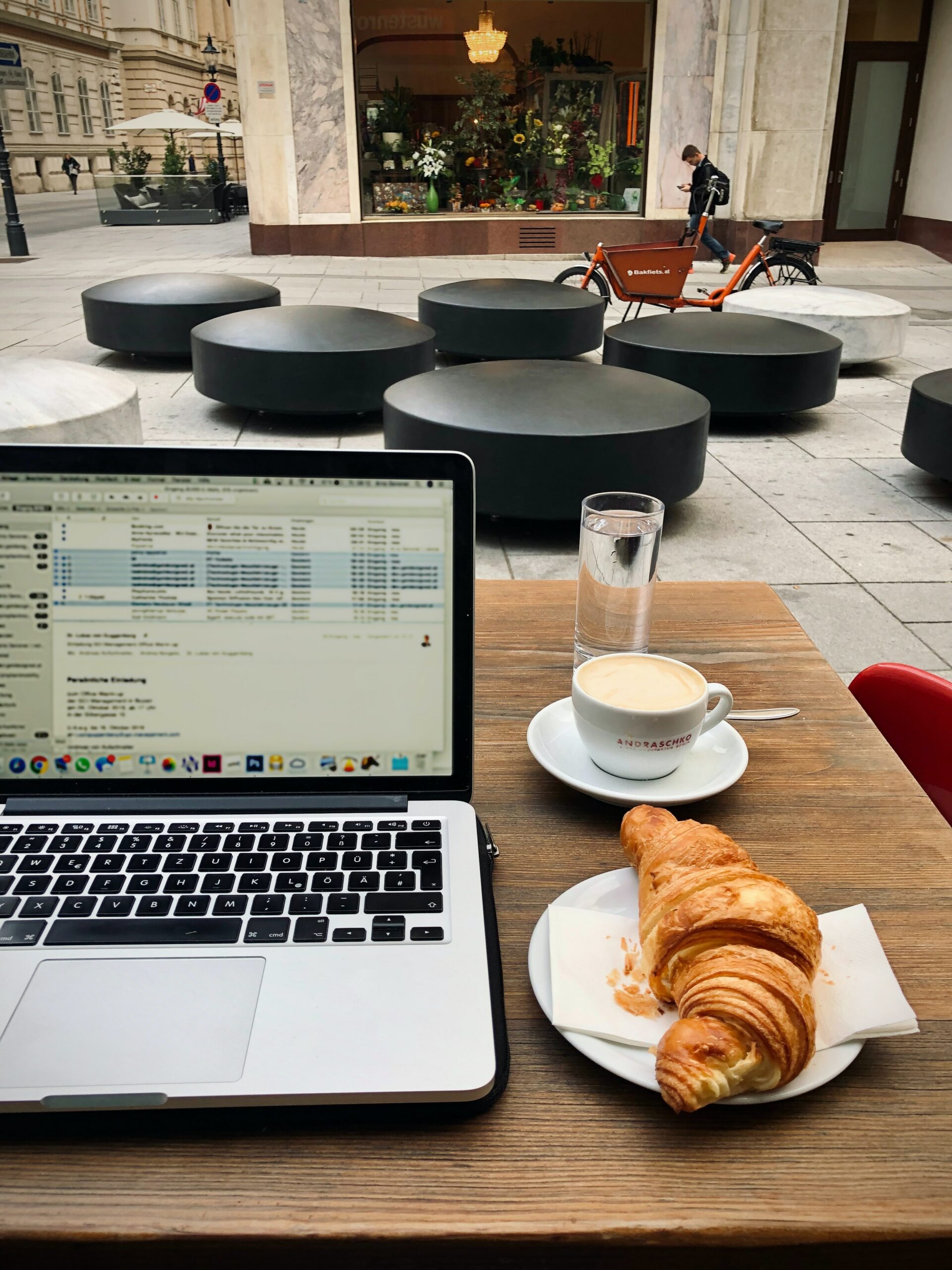 Laptop mit Kaffee und Croissant auf einem Café-Tisch in Wien