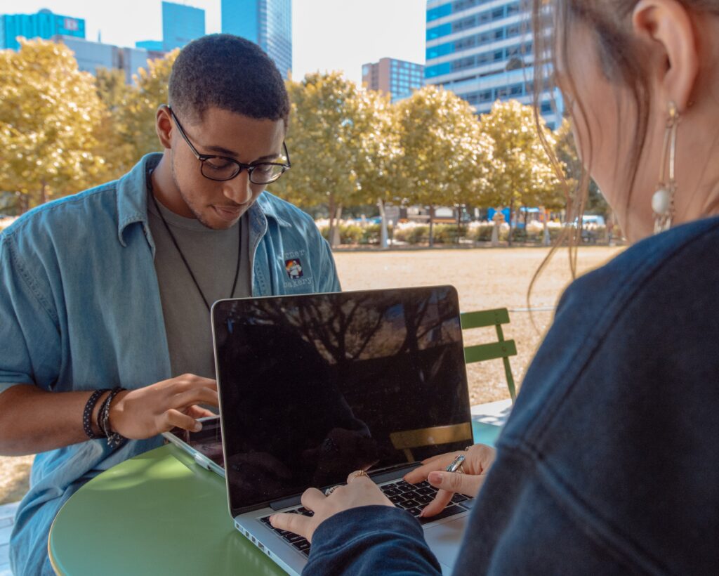 zwei Personen arbeiten draußen am Laptop