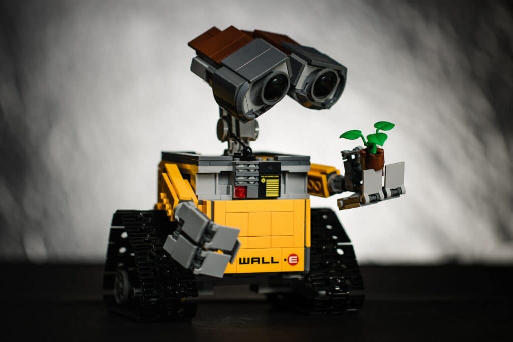 Lego Wall-E schaut auf eine Pflanze in seiner Hand