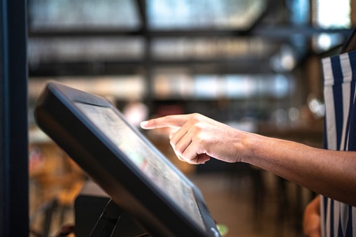 Zoom sur la main d'un équipier contrôlant le tableau de commande de son restaurant